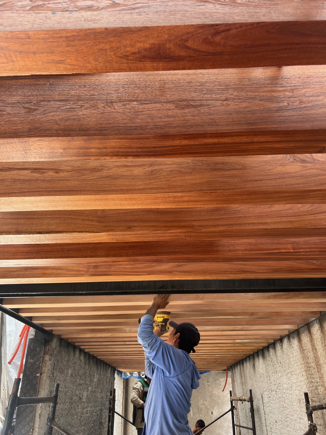 Techo de vigas de madera y un trabajador dando el acabado desde abajo.
