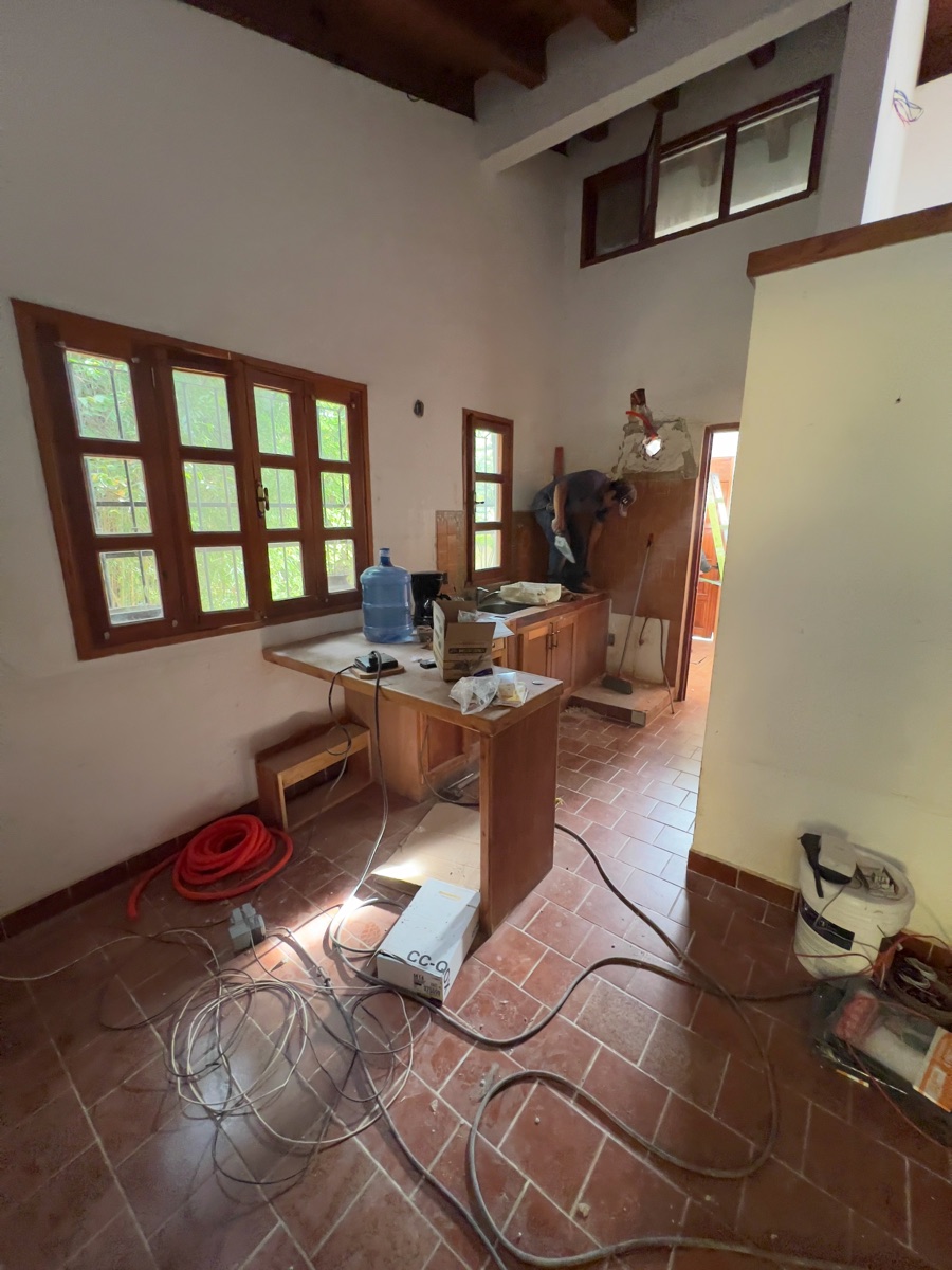 Interior de una casa con piso de loseta y ventanas de madera.